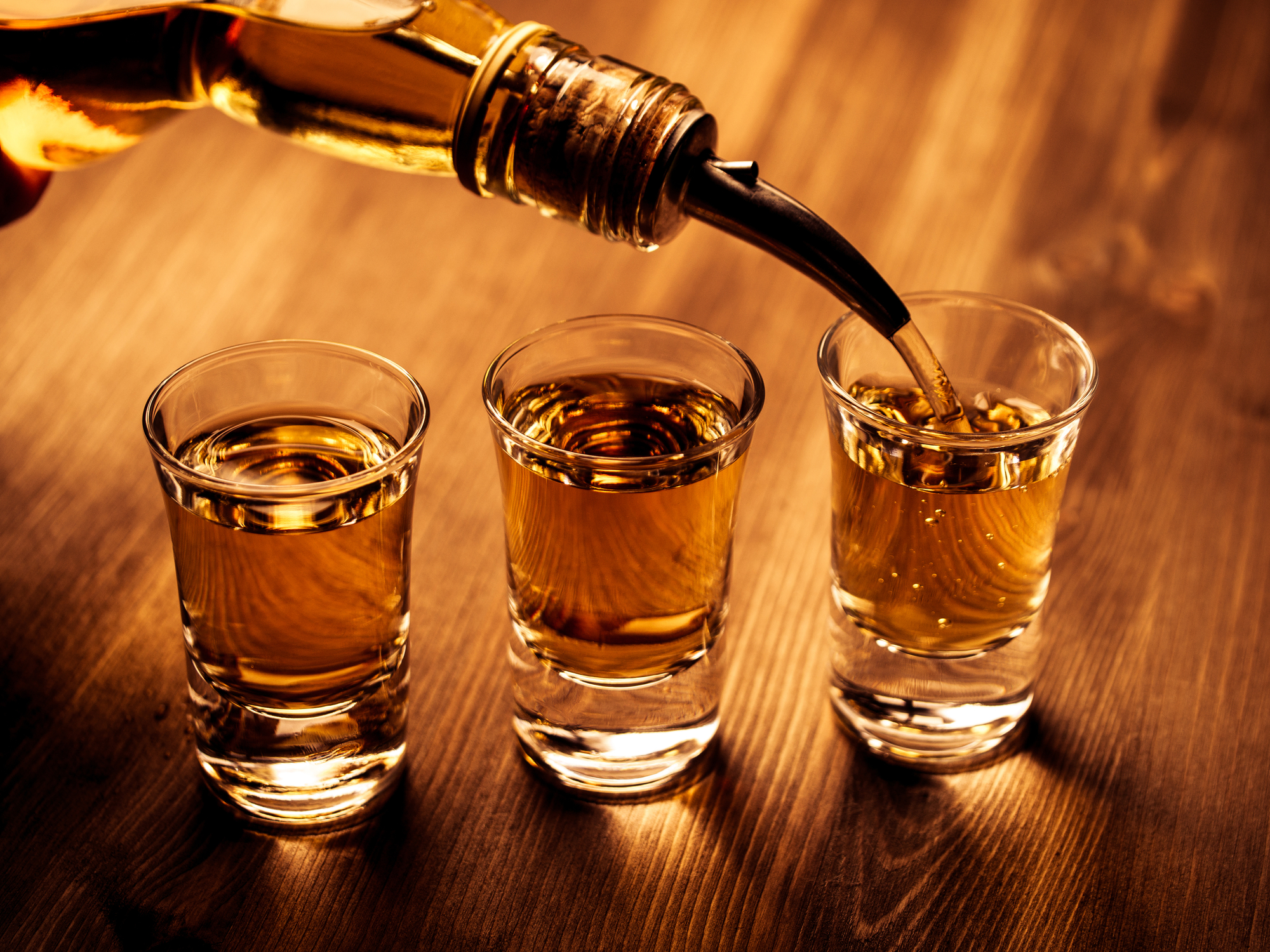 person pouring brown liquor into glasses - Anytime Bar Supplies Pour Spouts