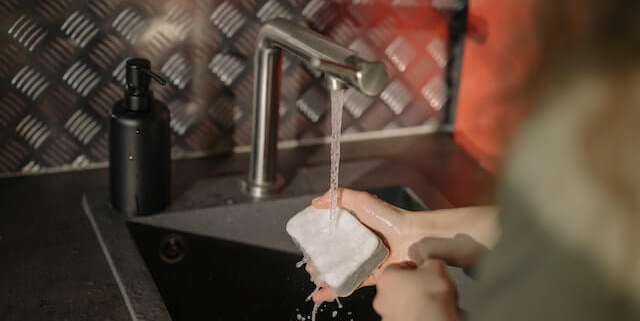 person wetting a sponge in a sink - Anytime Bar Supplies Pour Spouts