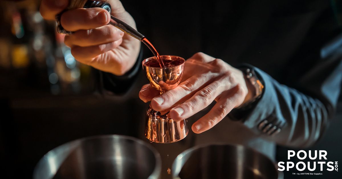 person pouring alcohol into a copper shot glass - Pour Spouts by Anytime Bar Supplies stainless steel pour spouts