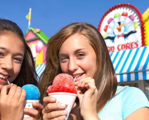 two girls at a fair eating snow cones - Pour Spouts